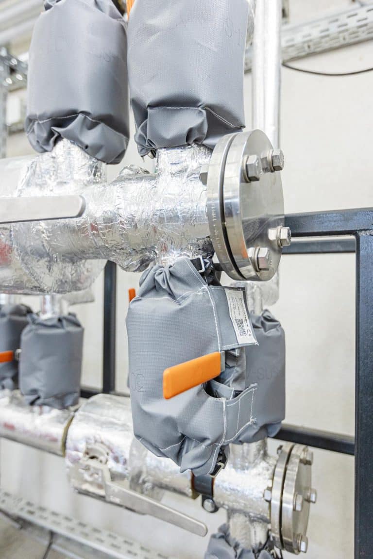 Isolierfabrik IFS-Plast25 Isolierkissen, IFS-MW20 Mineralwolle Rohrisolierung, Silikon Hitzeschutzschlauch an einer Heizung, Heizungsverteiler montiert, Wärmedämmung und Schallisolierung, Hochtemperatur-Isolierung, Dampfverteiler, Verrohung, Industrieanlage